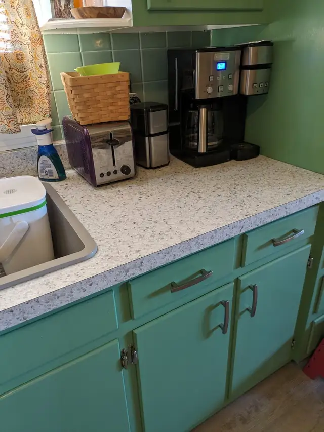 Speckled countertop installed by Danny over green painted cabinets, still in daily use a year and a half later